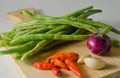 Some green beans, some red chili peppers, two cloves of garlic and a red onion Royalty Free Stock Photo