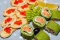 Some green sushi with red fish and pancakes with red caviar close-up.