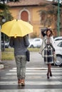 Some handsome and elegant young woman and man pass each other at a pedestrian crossing on a rainy day. Walk, rain, city Royalty Free Stock Photo