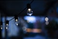 Some light bulbs lamp in a row in a beautiful dusk scene with some spotlights blurry background