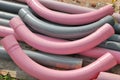 Some light pink and grey colored pipe elbows laid out at a construction site