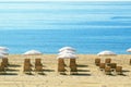 Some lounger and umbrelas next to the blue beach and white sand. Tourism concept.