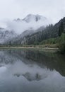 Some moody clouds fog the peak of a snow covered mountain Royalty Free Stock Photo