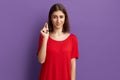 Some more, please. Doubting unsure young pretty brunette girl in red t-shirt shows small size gesture with fingers. Woman asks for Royalty Free Stock Photo