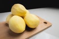 Some peeled potatoes on a wooden cutting board. On a white table against a dark background Royalty Free Stock Photo