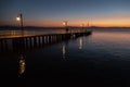 Some people on a pier at Trasimeno lake Umbria, Italy at dusk, with beautiful water reflections and warm colors Royalty Free Stock Photo