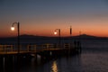 Some people on a pier at Trasimeno lake Umbria, Italy at dusk, with beautiful water reflections and warm colors Royalty Free Stock Photo