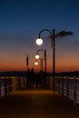 Some people on a pier at Trasimeno lake Umbria, Italy at dusk, with beautiful water reflections and warm colors Royalty Free Stock Photo