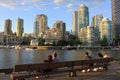 People sitting on the bench and looking at False Creek in downtown Vancouver in sunset light, Canada