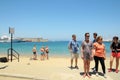 Some people are standing on the beach in Rhodos Island opposite of the castle.