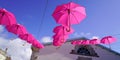 Pink umbrellas hang between houses street decorated Royalty Free Stock Photo