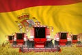 Some red farming combine harvesters on rural field with Spain flag background - front view, stop starving concept - industrial 3D