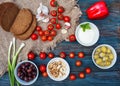 Some red fresh cherries, spring onions, coriander, cheese, garlic, olives in bowl, bread on dark rustic wooden background