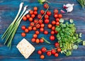 Some red fresh tasty cherries, green spring onions, green rosemary, leaves of coriander, sweet cheese, garlic on dark rustic wo