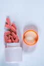 Some Scattered Red Tablets dropped from a medicine container on a white surface Royalty Free Stock Photo