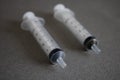 Two disposable syringes on a gray background