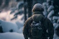 Some soldier, standing in a helmet and with a backpack, against the backdrop of a winter forest