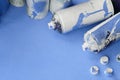 Some used blue aerosol spray cans and nozzles with paint drips lies on a blanket of soft and furry light blue fleece fabric. Class