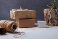 Some wrapped Christmas presents, paper roll, rope spool on white table, grey background. Winter holidays diy gifts wrapping Royalty Free Stock Photo