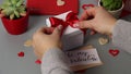 Somebody untie a bow on a valentine`s day gift with message BE MY VALENTINE