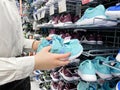 Someone chooses childrens or womens blue sneakers in the sports goods store Decathlon