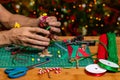 Someone Making holiday crafts. A Christmas Tree being created from a large Pine cone with ribbon, bells and pompoms