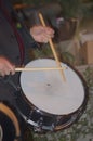 Someone plays the drum with the two wooden drumsticks