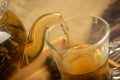 Someone pours flower tea brewed in a glass teapot into a glass mug. Close up Royalty Free Stock Photo