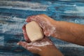 Someone is soaping their hands with a bar of soap on a wooden background. Close up. Regular hand washing with soap is a prevention Royalty Free Stock Photo