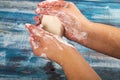 Someone is soaping their hands with a piece of toilet soap on a wooden background. Close up. Regular thorough hand washing with Royalty Free Stock Photo