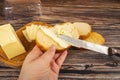 Someone spreads butter on fresh wheat toast with a knife and a wooden butter dish with a piece of butter and slices of cheese on a Royalty Free Stock Photo