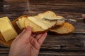 Someone spreads butter on fresh wheat toast with a knife and a wooden butter dish with a piece of butter and slices of cheese on a Royalty Free Stock Photo