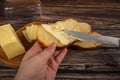 Someone spreads butter with a knife on fresh wheat toast, a piece of butter and slices of cheese in a wooden butter dish on a Royalty Free Stock Photo