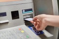 Someone takes off money from outdoor bank terminal, inserts plastic credit card in atm machine, going to withdraw money and get sa