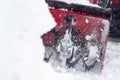 Someone uses a snowthrower outdoors in winter while it is snowing