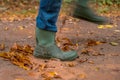Someone walks through the forest with rubber boots and enters a puddle
