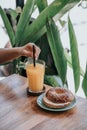 Someone was holding a straw in a drink glass and a burger bagel with vegetables and cheese on the plate