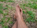 Someone& x27;s feet are resting on the ground, a little green grass. Royalty Free Stock Photo