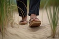 a pair of feet in sandals standing in sand
