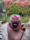 someone hand holding a jar filled with overnight oats with strawberry topping