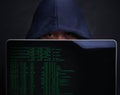 Someones been keeping a watch of your every move online. Portrait of a hacker holding up a laptop against a dark Royalty Free Stock Photo