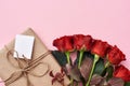 Something special for her: bouquet of fresh red roses and homemade gift in kraft wrapping paper Royalty Free Stock Photo