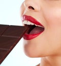 Something sweet. Studio shot of an unrecognizable young woman biting into a slab of chocolate against a light background