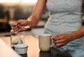 Something to sweeten the day. a woman making a cup of coffee at home.