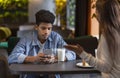 Bored black guy looking at smartphone during date time