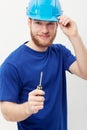 Sometimes the simple tools work best. Portrait of a young man wearing a hardhat and holding a screwdriver.