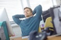 Sometimes you have to take a step back. a content young office worker leaning back in his chair with his hands behind