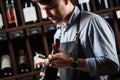 Sommelier holding wine bottle in cellar on background of shelves Royalty Free Stock Photo