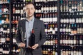 Sommelier man holds bottle red wine and glass on dark background restaurant