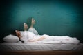 Somnambulist rising from bed near green wall indoors, multiple exposure. Sleepwalking Royalty Free Stock Photo